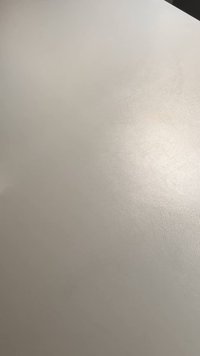 Smooth, light gray surface with a subtle texture, reflecting light in varying shades, creating a soft sheen without any distinct patterns.