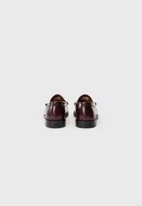 Tumedast burgundia nahast loafersid läikiva viimistluse, ümarate varvaste, lame musta tallaga ja minimalistliku disainiga. Standardsed kontsade kõrgus.