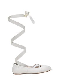 Ballerine blanche plate avec des brides croisées et de longs rubans blancs s'étendant vers le haut pour s'enrouler autour de la cheville, présentée sur un fond blanc.