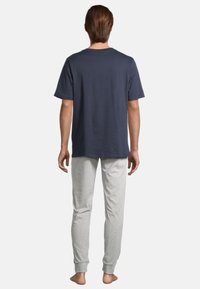 T-shirt en coton bleu marine à manches courtes associé à un pantalon de pyjama long en coton gris clair avec des poignets côtelés, vu de dos.