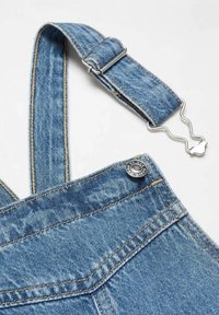 Siniset collegehaalarit, joissa on säädettävät hihnat. Vaalea sininen väri, jossa on hieman haalistunut pinta, hopeiset yksityiskohdat ja erottuvat ompelutavat.