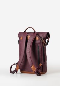 Zaino roll-top bordeaux con dettagli in pelle, spallacci regolabili e tasca laterale con zip; superficie texturizzata, design strutturato, stile minimalista.