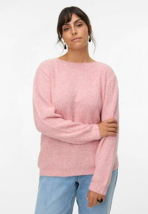 Pull en tricot rose avec une surface texturée, col rond et manches longues, associé à un jean en denim bleu clair.
