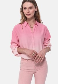 Camicia button-down rosa chiaro con effetto ombré, a maniche lunghe, indossata aperta sopra pantaloni rosa abbinati. Tessuto liscio, vestibilità casual e dettagli con doppio polsino.