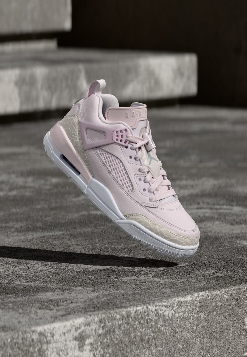 Ροζ ανοιχτό και μπεζ παπούτσι τύπου ψηλής κορυφής αιωρείται στον αέρα πάνω από σκάλες από σκυρόδεμα, με ορατή υφή στη σόλα και κορδόνια.