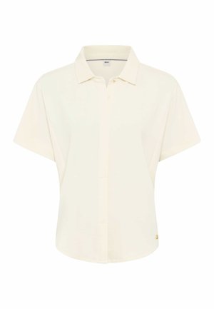 Polo manches courtes crème avec col, devant partiellement boutonné, et petit logo doré près de l'ourlet du côté droit.