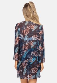 Przezroczysta sukienka z długimi rękawami, na ciemnym tle, z kolorowym wzorem liści w odcieniach niebieskiego, różowego i zielonego, o luźnym kroju.