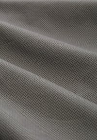 Strukturiert grauer Stoff mit einem geometrischen Muster, das feine Linien und kleine Dreiecke zeigt und ein dezentes, sich wiederholendes Design schafft.
