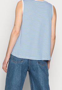 Blå och vit randig ärmlös topp med avslappnad passform, kombinerad med högmidjade denimshorts med bakfickor och en texturerad yta.