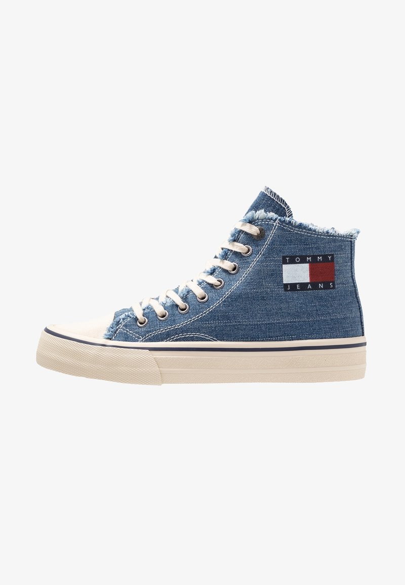 Sneakers high-top in denim blu con bordi sfilacciati, dotati di una suola in gomma beige e un'etichetta con logo in rosso, bianco e blu.
