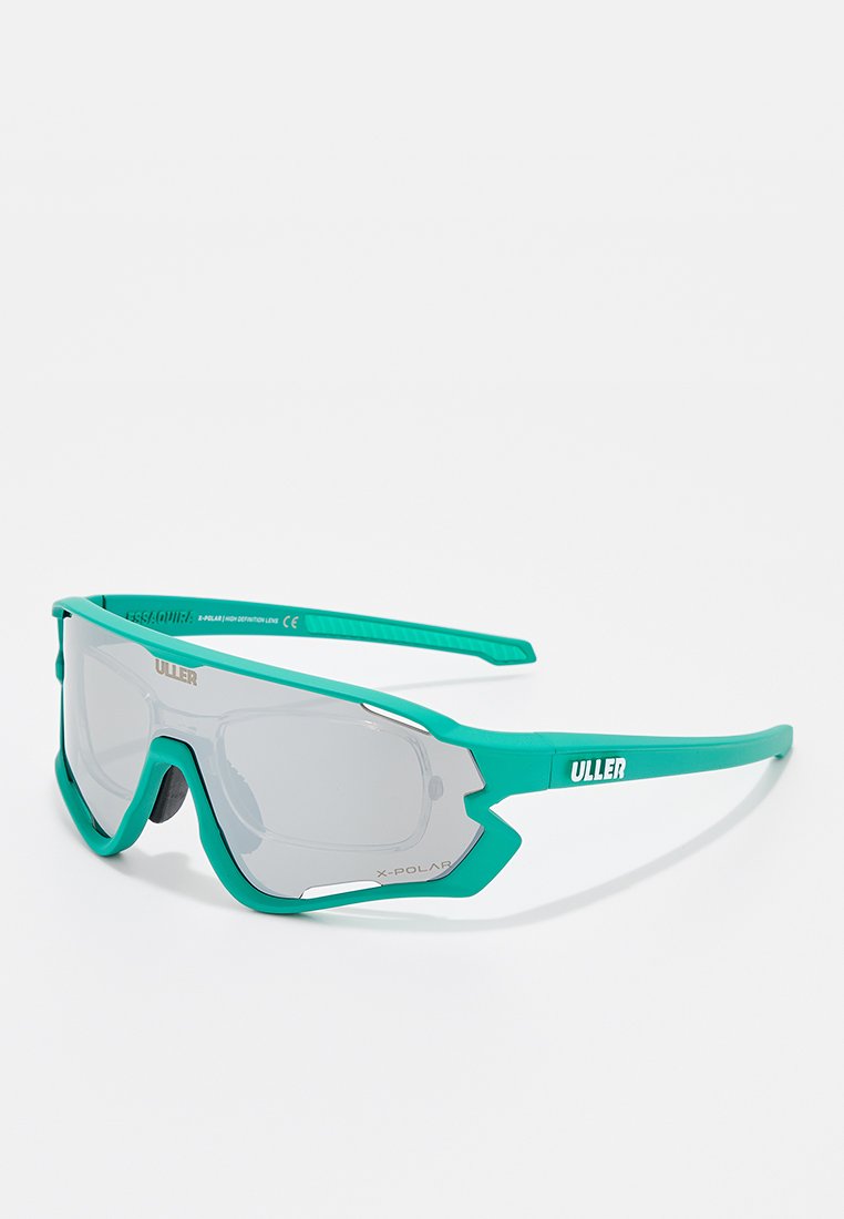 Lunettes de sport avec une monture en plastique turquoise, de grandes verres gris, un design angulaire et le logo "ULLER" sur le côté. Poignées texturées sur les branches.