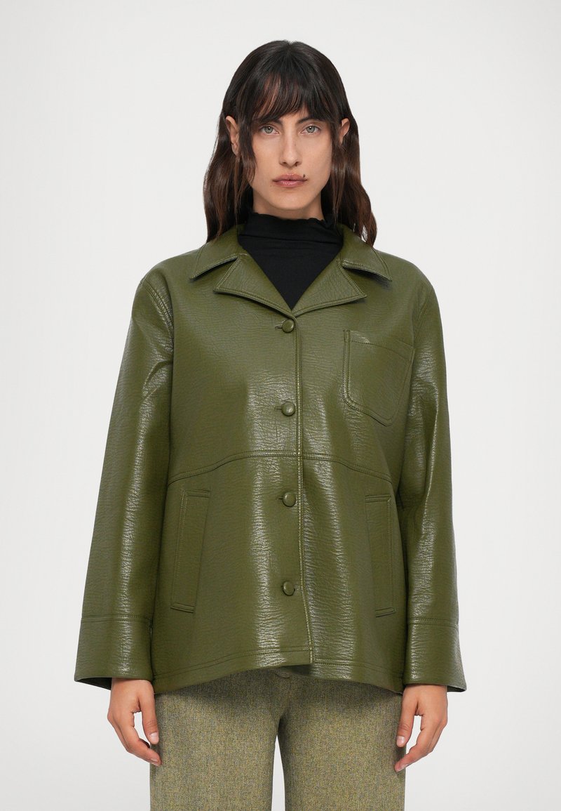 Giacca in ecopelle verde con collare a punte, tasche frontali e chiusure con bottoni. Presenta una finitura testurizzata e una vestibilità rilassata.