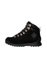 Bottes de randonnée noires en daim avec quincaillerie dorée métallique, accents noirs texturés et semelle à crampons pour une meilleure traction. Elles sont équipées de lacets durables.