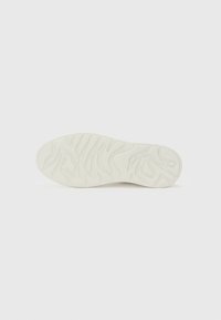Weiße Sneaker-Sohle mit strukturiertem Wellenmuster. Aus Gummi gefertigt, mit geschwungenen Rillen und einer abgerundeten Zehenform. Minimalistisches Design.