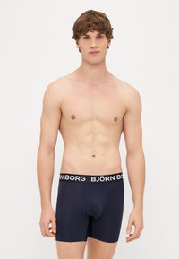 Jūras spēku boxer apakšveļa ar melnu jostu, kurā ir baltas "BJÖRN BORG" burtu. Gluda auduma un pieguļošs dizains ērtībai un atbalstam.