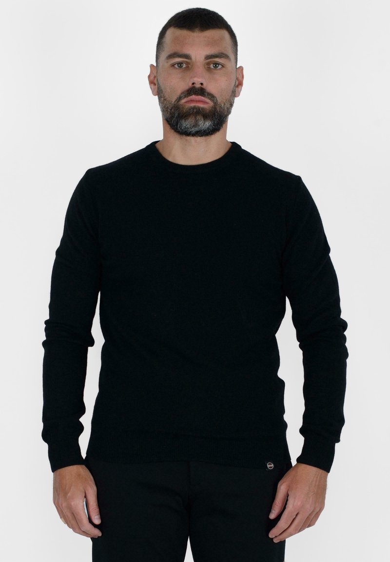 Maglione nero a maglia con maniche lunghe, scollo rotondo e orli a coste. Texture morbida e design aderente. Esibito su uno sfondo neutro.