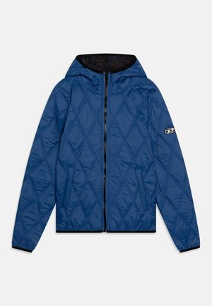 Giacca blu trapuntata con cappuccio, dotata di zip frontale, fodera nera, dettagli sui polsini in elastico e un logo sulla manica sinistra.