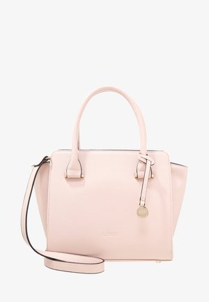 Sac à main structuré rose clair avec doubles poignées supérieures, une bandoulière amovible et une petite étiquette ronde dorée sur la poignée avant droite.