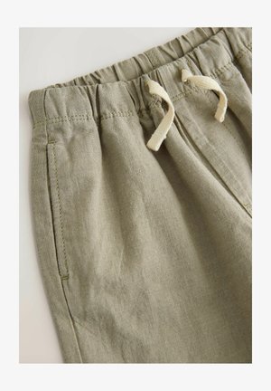 Bež kratke hlače iz lanu z elastičnim pasom, opremljene z vrvico za prilagajanje in bočnimi žepi. Mehka tekstura z zračno obdelavo.