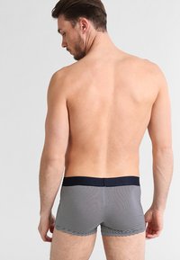 Pruhované námořnické modré a bílé boxerky s elastickým pasem, které mají těsně přiléhající střih a hladkou texturu. Minimalistické označení.