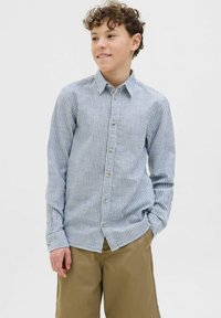 Camicia button-up con un motivo a righe blu chiaro e bianche, maniche lunghe e bottoni dorati, abbinata a pantaloni corti color khaki.