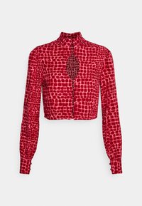 Blusa corta vermelha com mangas longas, apresentando um padrão de bolinhas, fechamento frontal com botões e um detalhe recortado distinto na gola.