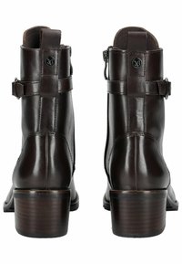 Stivali ankle in pelle marrone con finitura lucida, dotati di cerniere laterali, dettagli con fibbia e tacco impilato per un'ulteriore elevazione.