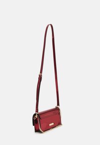 Sac bandoulière métallique rouge avec une texture lisse, une forme rectangulaire et un accent en chaîne dorée. Équipé d'une sangle ajustable pour plus de polyvalence.