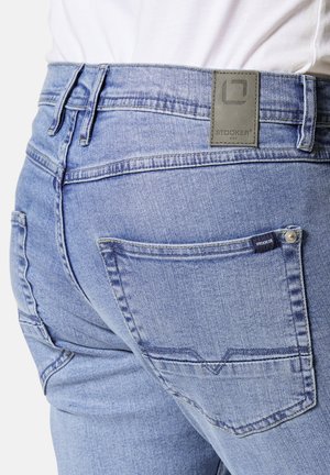 Hellblaue Jeans aus Denim mit geradem Schnitt, Gesäßtaschen und einem grauen Lederlabel mit dem Markenlogo an der Bundweite.