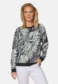 Zwart sweatshirt met lange mouwen, voorzien van een grijs tropisch bladdessin, geribbelde manchetten en een ronde halslijn. Gecombineerd met lichtgekleurde broek.