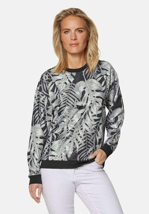 Black long-sleeve sweatshirt featuring a gray tropical leaf pattern, ribbed cuffs, and a round neckline. Paired with light-colored pants.