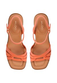 Koraalrode sandalen met een kruisbandontwerp, glad synthetisch materiaal, vierkante neusvorm en een gevoerde tan binnenzool met gouden branding.