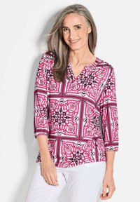 Mustered Langarmshirt mit rosa, weißen und schwarzen Blumenmotiven, V-Ausschnitt und entspannter Passform mit gerafften Ärmeln.