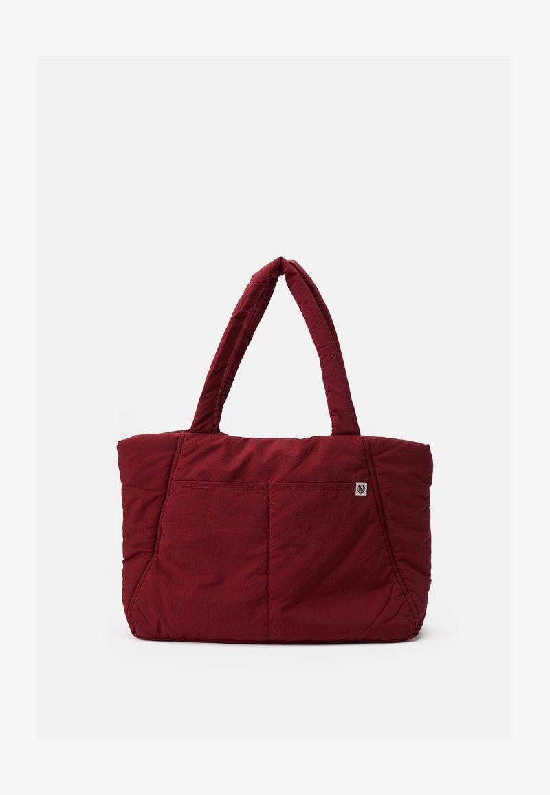 Red quilted tote bag with two handles, featuring a front pocket, soft texture, and rectangular shape, suitable for daily use.
