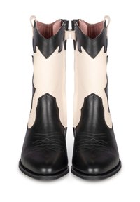 Bottines en cuir noir et crème avec un bout pointu, des coutures décoratives, un design découpé et un dos haut. Dotées d'onglets latéraux pour un enfilage facile.