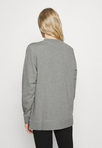 Sudadera gris con cuello redondo, mangas largas y un corte ligeramente oversize. Fabricada en un tejido suave con una textura lisa.