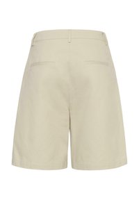 Short beige taille haute avec passants pour ceinture et deux poches passepoilées arrière, vu de dos sur fond blanc.
