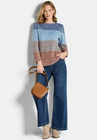 Maglione a maglia con righe orizzontali blu e marroni, abbinato a jeans a gamba larga blu e una borsa a tracolla beige. Indossati stivaletti alla caviglia in suede.