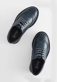 Blå læder brogues med perforerede mønstre, rund tå og grå snørebånd. Har en let sort sål og polstret indersål.