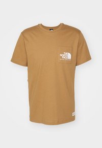 Brązowy t-shirt z krótkim rękawem i okrągłym dekoltem, wykonany z bawełny. Posiada kieszonkę z przodu z logo "The North Face" oraz małą metkę na dole.