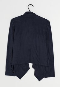 Chaqueta azul marino con una textura suave, de mangas largas y un dobladillo asimétrico. Presenta un cuello y una costura trasera para un aspecto entallado.