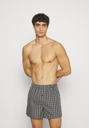 Boxer shorts gris à carreaux avec une taille élastique, comportant un bouton frontal unique. Tissu léger avec un motif à carreaux.