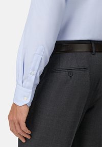 Lichtblauw gestreepte overhemd met enkele knoopmanchet, gecombineerd met donkergrijze textuurbroek met een achterzak en knopdetail.