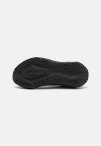 Schwarze Sportschuhsohle aus strukturiertem Gummi, mit mehreren Mustern für Grip und Flexibilität, flache Form und keine sichtbaren Logos.