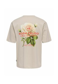Camiseta de algodón beige con un gran gráfico de una rosa blanca con hojas verdes y texto rojo en la parte posterior, que incluye "Rosa Pálido."