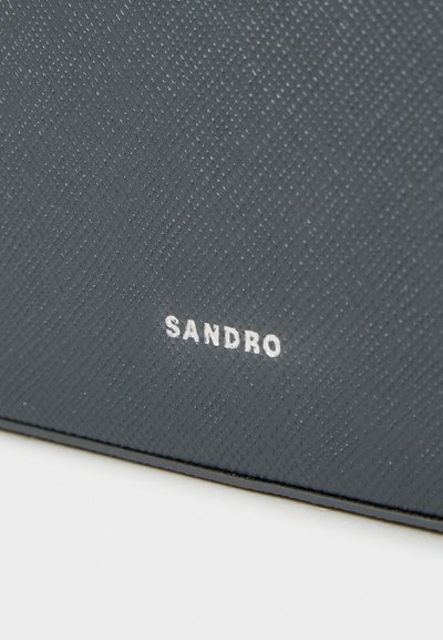 Mörkblått texturerat plånbok med ett subtilt herringbone-mönster, med en vit "SANDRO"-logotyp i botten. Slätt och smidigt material.
