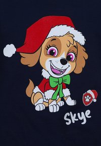 Grafica di un cane cartone animato che indossa un cappello di Babbo Natale rosso, un fiocco verde e un abbigliamento festivo, su uno sfondo blu navy. Le caratteristiche includono grandi occhi e dettagli di impronte di zampe.