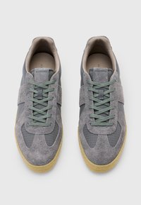 Sneaker grigie realizzate con un mix di camoscio e materiale in rete, con un motivo testurizzato, lacci verdi e suola in gomma naturale.