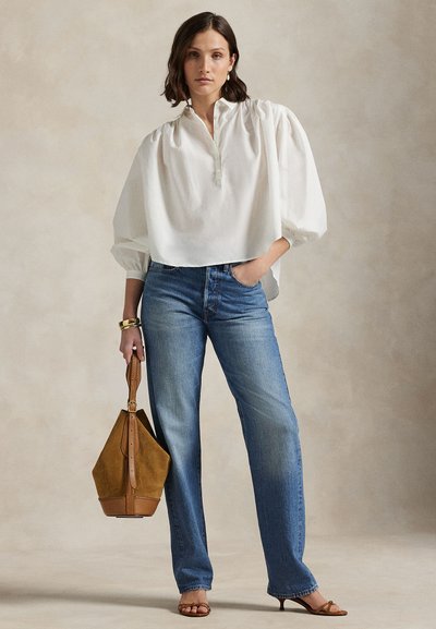 Hvit, vidt sittende bluse med puffede ermer, kombinert med blå jeans med rette ben. Brun semsket veske og brune sandaler med stropper.