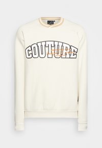 Cream sweatshirt with a crew neck, featuring bold "COUTURE" text in black and orange. Soft fabric, ribbed cuffs, and hem.